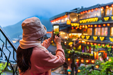 Young female tourist taking a photo of Jiufen old street landmark and popular attractions in Taiwan