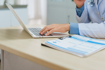 Asian male psychiatrist provides online counseling at his desk, using a laptop to connect with...