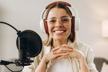 Smiling woman radio host recording podcast in studio