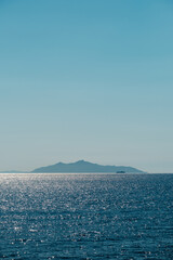 A ferry passes the Italian island of Elba silhouetted by the morning sunlight glistening off the Mediterranean sea