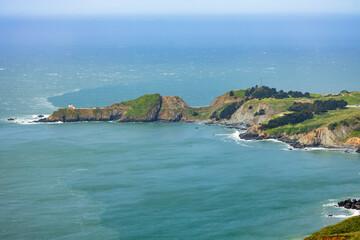 Scenic panoramic view of Marin Headlands with winding road, lush green hills, and Pacific Ocean...