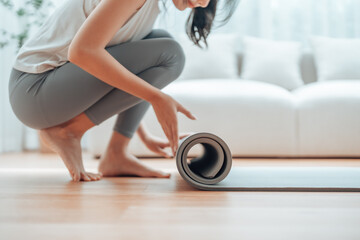 Young Asian woman doing yoga, twisting on a mat in the living room at home