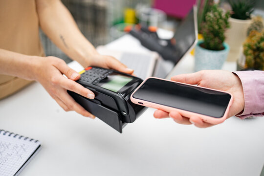 A customer makes a contactless payment at a florist shop using a smartphone device.