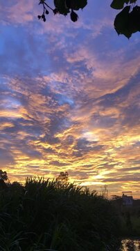 Stunning sunset over a serene beach with dramatic clouds and a vibrant orange sky. Gentle waves roll onto the shore as the sun dips below the horizon, casting warm golden hues across the landscape