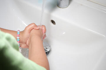Child washing hands at a sink in a bathroom