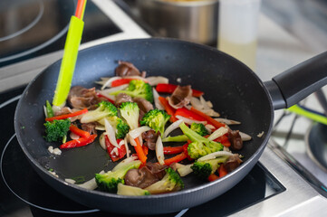 Beef and vegetables are fried in a frying pan. 