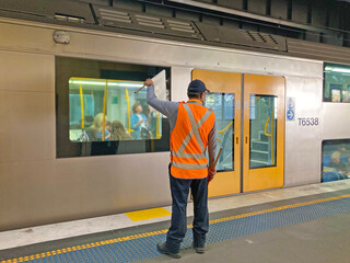 A rail worker waving a white flag signals to the train driver that it is safe to proceed