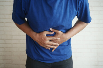 Person in blue shirt holding abdomen in pain