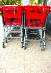 Red, plastic upper section shopping carts, pushed into each other in front of a store, in two rows, from a close distance.