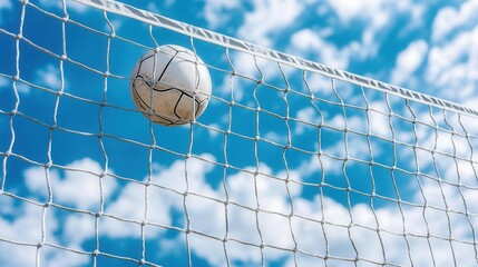 summer concept. Soccer ball hitting the net under a blue sky with clouds.