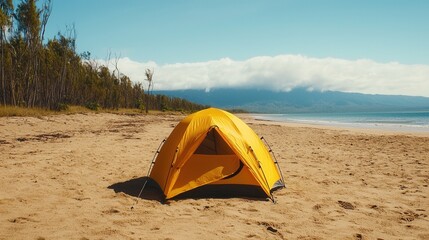 summer concept. A bright yellow tent on a sandy beach with mountains in the background.