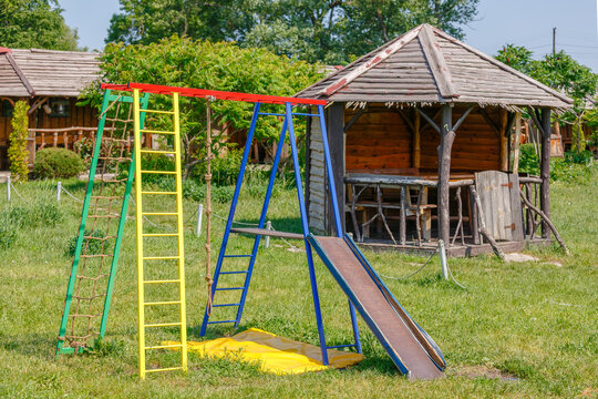Colorful Playground Slide and Climbing Frame Near Rustic Gazebo - Powered by Adobe