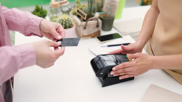 A customer is using a credit card to make a purchase at a florist shop, focusing on modern payment methods.