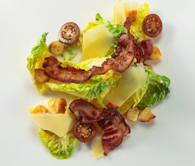 Salad with grilled bacon, hard cheese, tomato, and croutons.