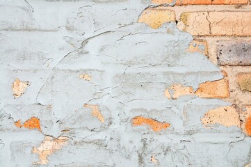 The image displays an old brick wall covered with cracked and peeling plaster.