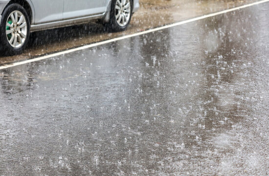 Fototapeta A car is driving down a wet road with rain falling from the sky