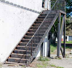 A staircase with a railing is shown in front of a white building