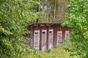 Idyllic old wooden outhouse on a meadow by the forest