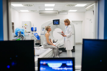 Doctor explaining CT scan results to female patient in imaging room