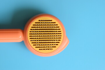 pastel orange comb on blue background, hair brush for pet