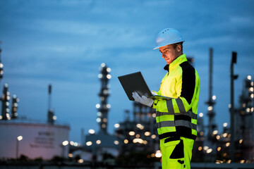 Factory worker engineer man using laptop computer for system maintenance at outdoor refinery site during night shift, working in industrial environment with focus and precision. © DJ Creative Studio