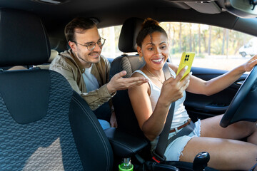 Woman driving car using mobile phone while man giving directions