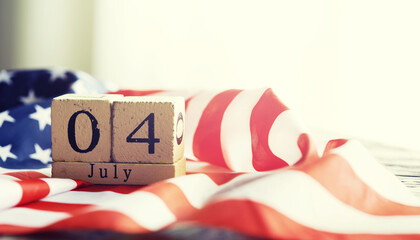 Cube shape calendar for July 04 on wooden table on usa flag background