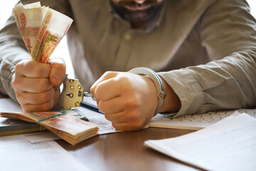 Hands in handcuffs behind, holding five thousand rubles. Concept of corruption