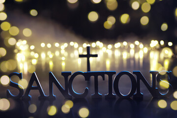 word sanctions spelled in letters on table made of wooden block letters with dramatic lighting and...