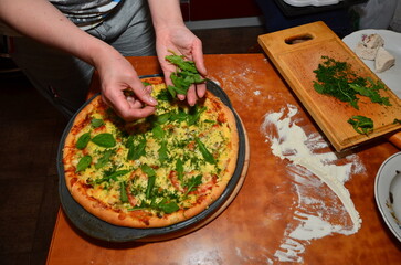woman preparing pizza in apartment hands and product visible