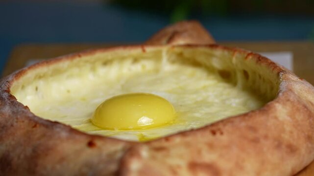 Georgian khachapuri with soft baked dough, melted cheese filling, and raw egg yolk in the center.