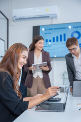 Group of business partners gathered around open laptop discussing company development strategies in...