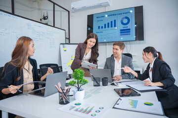 Group of business partners gathered around open laptop discussing company development strategies in modern office.