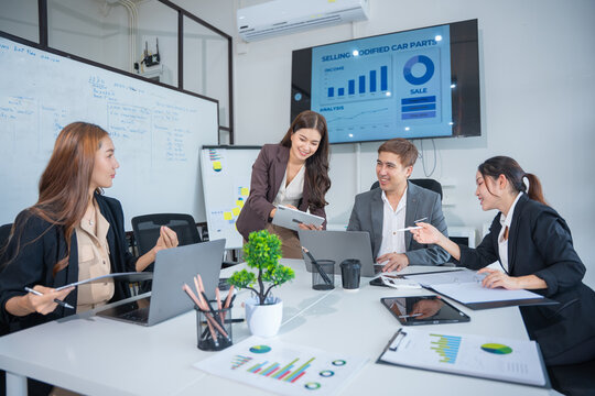Group of business partners gathered around open laptop discussing company development strategies in modern office.