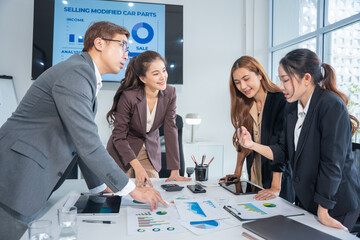 Group of confident professional business people pointing at graphs and charts to analyze marketing data to plan new sales strategies to increase productivity in modern office.