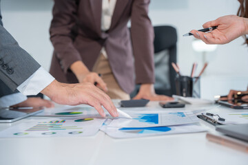 Group of confident professional business people pointing at graphs and charts to analyze marketing data to plan new sales strategies to increase productivity in modern office.