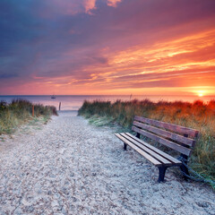Embracing Freedom: A Lonely Bench Overlooking a Colorful Sunset by the Sea