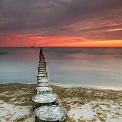 Timeless Shores: Weathered Wooden Groynes Under a Vibrant Sunset