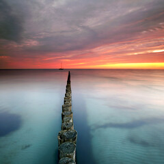 Colorful Sunset Reflections Over Ancient Wooden Groynes