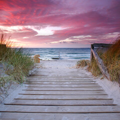 a footpath of wooden planks to the beautiful beach at the sea, amazing sunset light