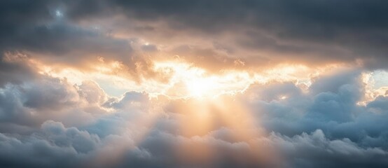 Obraz premium Radiant sun beams piercing through dramatic clouds at sunrise or sunset creating a peaceful and awe-inspiring atmosphere