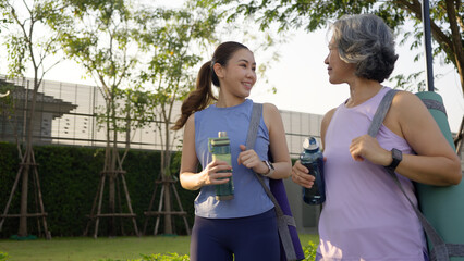 Young adult child and mature middle age old mum public park walk workout with yoga mat water...