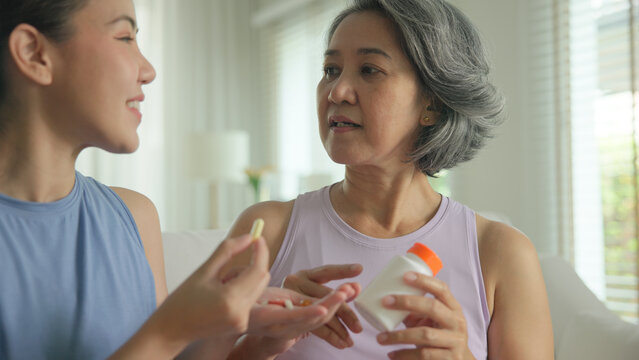 Young adult child give advice to middle age old mum. Love health care older aged mom asia elder people at home happy family help protect aging asian life. Vitamin d c e k zinc omega 3 fish oil pill.