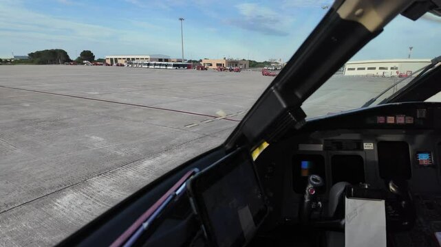 An immersive cockpit view of the hand of a caucasian pilot doing hand signals to tha ground staff while starting up the engine during the push-back maneuver.