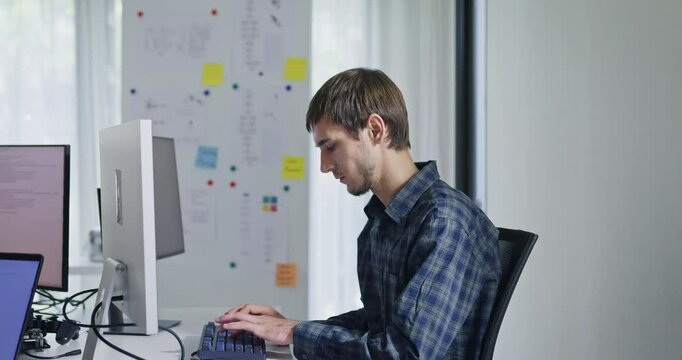 Portrait confident smiling male programmer working with robotics code AI software and looking at camera in tech office. Artificial intelligence dashboard, robotics, user interface, machine learning.