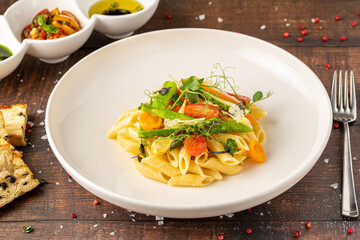 Creamy penne pasta with asparagus, cherry tomatoes and microgreens