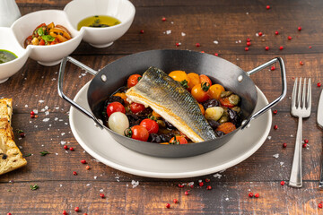 Seared sea bass fillet with cherry tomatoes and braised vegetables