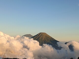 View of Mount Sindoro and Mount Sumbing among thick white clouds. Bright blue sky and dramatic...