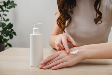 Female hands applying moisturizer cream or lotion. Hand skin care, treatment skin care body concept. Routine in the morning