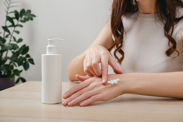 Female hands applying moisturizer cream or lotion. Hand skin care, treatment skin care body concept. Routine in the morning